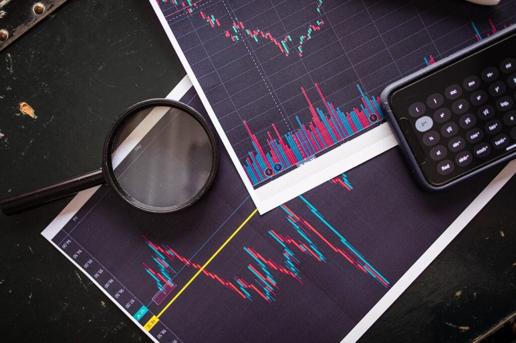 Stock Market Charts Analyzed With A Magnifying Glass And Calculator For Financial Research.